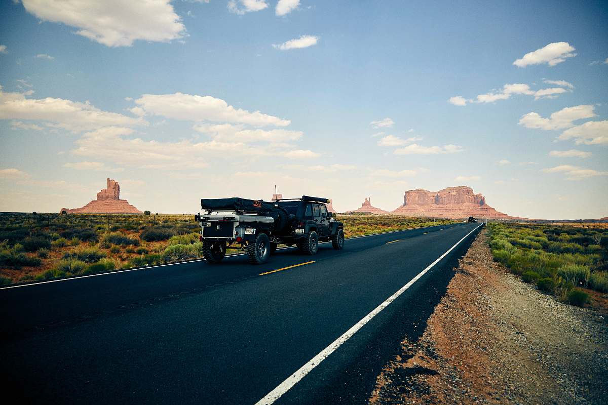 road black vehicle towing trailer on black road during daytime oljato-monument valley